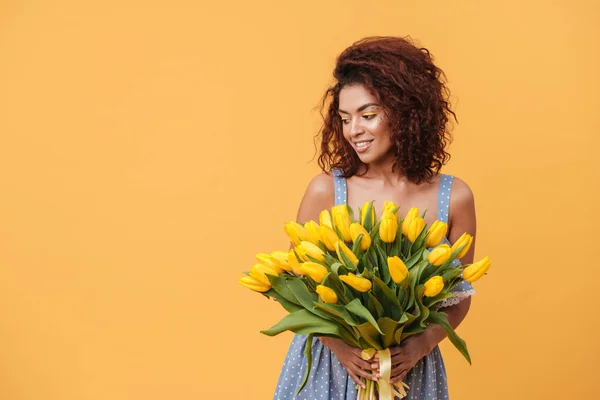 Smiling African woman holding bouquet of flowers — Stock Photo, Image