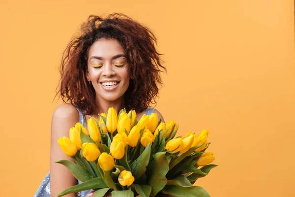 Smiling African woman with closed eyes holding bouquet of flower — Stock Photo, Image
