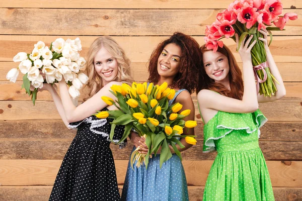 Tres mujeres complacidas sosteniendo ramos de flores —  Fotos de Stock