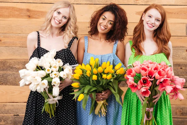 Tre smukke kvinder med buketter af blomster - Stock-foto