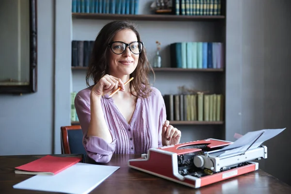 Portrait of a mature smiling authoress sitting at the desk — Stock Photo, Image