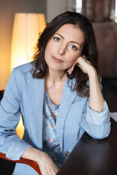 Erstaunliche Frau sitzt drinnen am Tisch. — Stockfoto