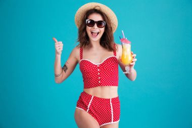 Kamera başparmak gösteren kokteyl bakarak bir neşeli kadın.