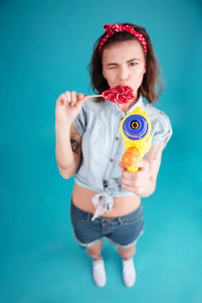 Женщина, стоящая в изоляции, держит водяной пистолет и конфеты . — стоковое фото