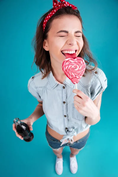 Mulher sorridente comendo doces segurando água doce aerada . — Fotografia de Stock