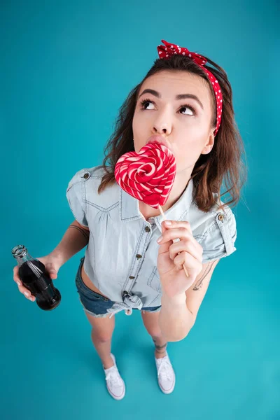 Mujer seria de pie aislada comiendo dulces sosteniendo aireador agua dulce . — Foto de Stock