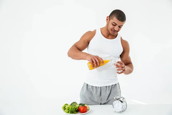 Handsome young sportsman holding glass of juice. — Stock Photo, Image