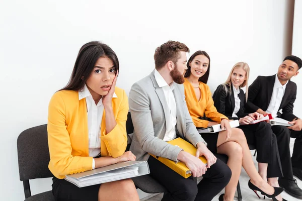 Förvirrad dam som sitter nära kollegor i office — Stockfoto