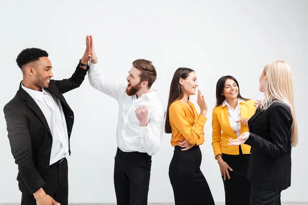Sonrientes colegas equipo de negocios de pie en la oficina da un high-five —  Fotos de Stock