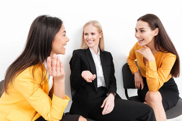 Felices colegas mujeres sentadas en la oficina hablando entre sí . — Foto de Stock