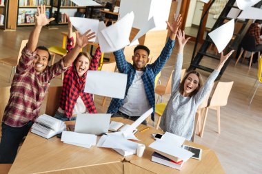 Mutlu öğrenciler Kitaplığı'nda oturan gazeteyi atmak.