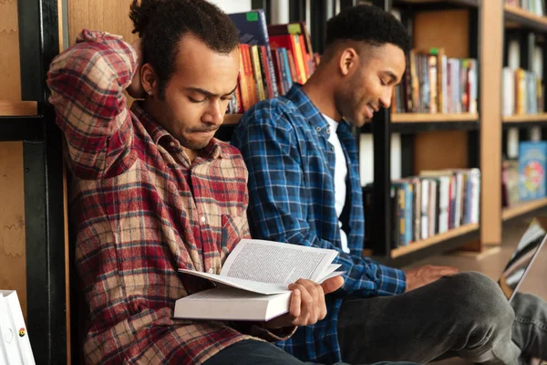 Jovem concentrou dois homens africanos lendo livros usando laptop — Fotografia de Stock