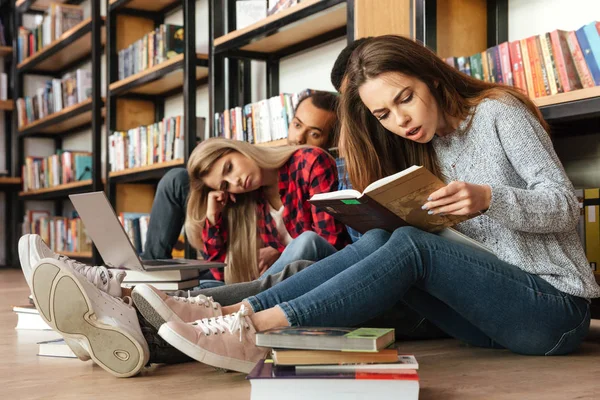 Втомлені студенти сидять у бібліотеці на підлозі читають книги — стокове фото