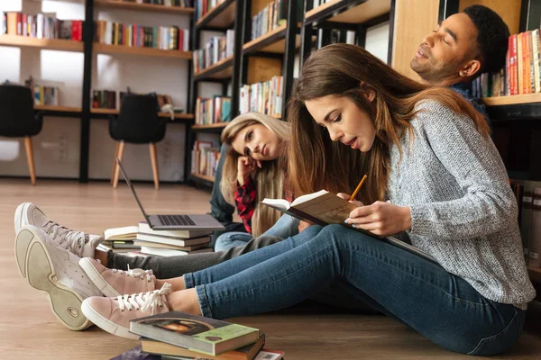 Studenten zitten in bibliotheek op verdieping lezingsboeken geconcentreerd. — Stockfoto