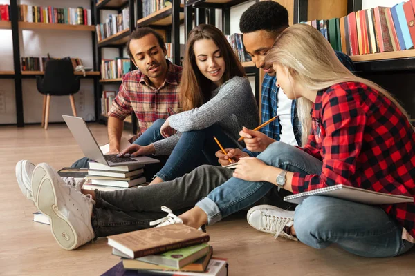 Ung koncentrerad elever sitter i biblioteket på plan — Stockfoto