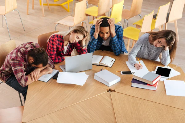 Zmęczony studentów siedzi w bibliotece. — Zdjęcie stockowe