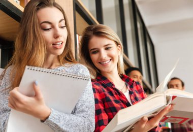 Konsantre iki genç bayanlar öğrenci kitap okuma