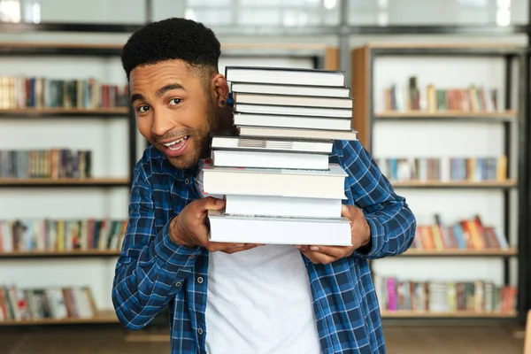 Jovem afro-americano estudante do sexo masculino segurando pilha de livros — Fotografia de Stock
