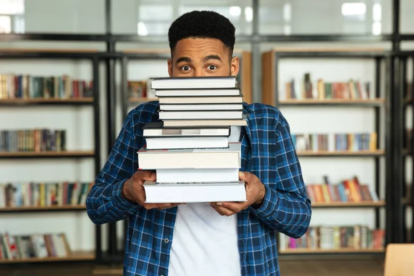 Jonge afro Amerikaanse mannelijke student die stapel boeken houden — Stockfoto