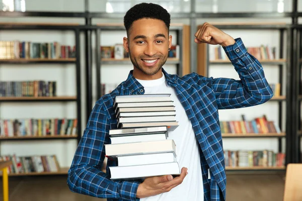 Jovem estudante africano confiante segurando pilha de livros — Fotografia de Stock