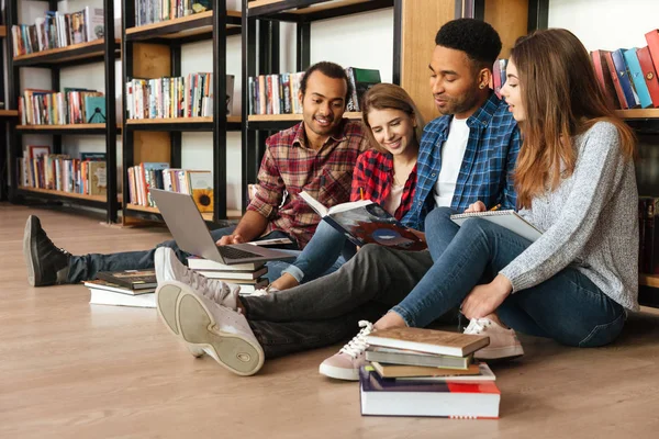 Koncentruje studentów siedzi w bibliotece na podłodze przy użyciu laptopa — Zdjęcie stockowe