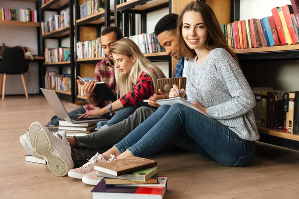 Estudiantes concentrados sentados en la biblioteca en el piso — Foto de Stock