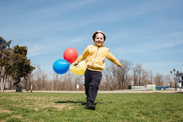 Mosolyogva séta kint park léggömbökkel gyermekek, kisfiú. — Stock Fotó