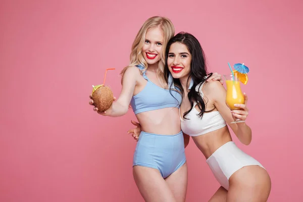Χαρούμενος νεαρός δύο κυρίες ντυμένες στα μαγιό πίνοντας κοκτέιλ. — Φωτογραφία Αρχείου