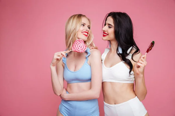 Due giovani donne sexy in costume da bagno in posa con lecca-lecca — Foto Stock