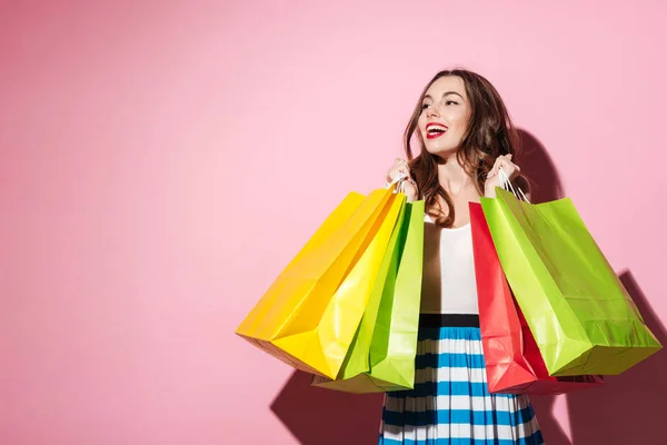 Mosolygó fiatal nő vevő gazdaság bevásárló táskák, és keres el — Stock Fotó