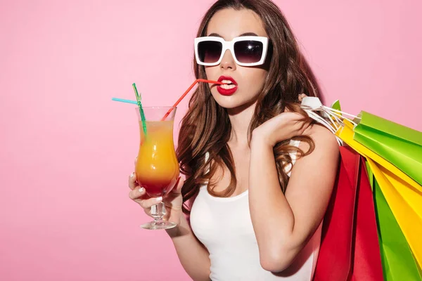 Dívka v sluneční brýle drží barevné tašky a pít koktejl — Stock fotografie