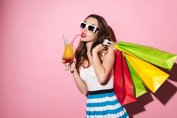Meisje in zonnebril houdt van kleurrijke boodschappentassen en cocktail drinken — Stockfoto