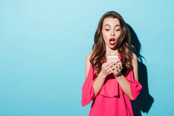 Sorprendido chica joven en vestido mirando el teléfono móvil — Foto de Stock