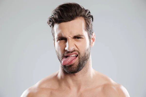 Портрет засмученого роздратованого голого бородатого чоловіка, що показує язик — стокове фото