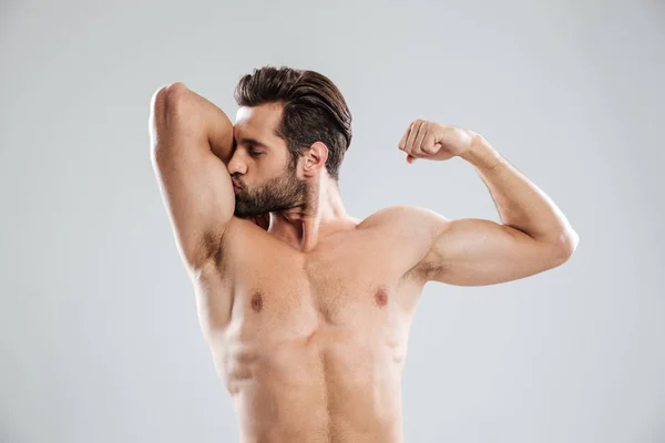 Stilig ung naken man visar och kysser hans biceps — Stockfoto