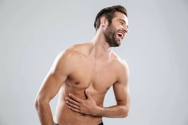 Portrait of a bearded shirtless man doubling up with laughter — Stock Photo, Image