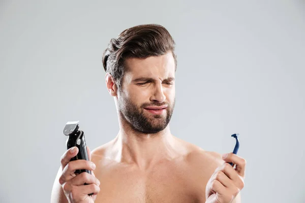 Retrato de un joven dudoso eligiendo afeitadora —  Fotos de Stock