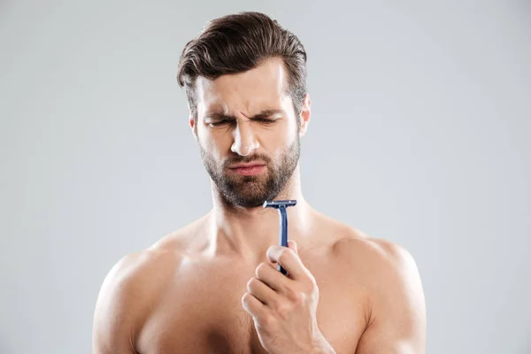 Porträt eines nachdenklichen bärtigen nackten Mannes, der auf Rasiermesser blickt — Stockfoto