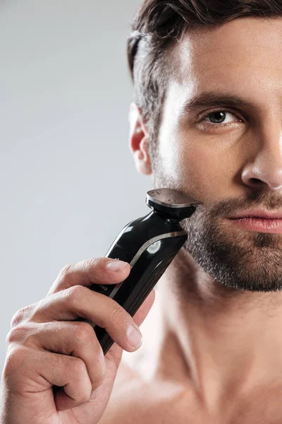 Guapo joven sosteniendo afeitadora eléctrica — Foto de Stock