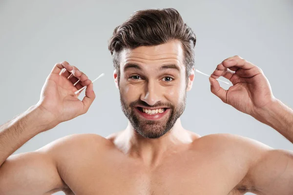Hombre sonriente usando palos para las orejas —  Fotos de Stock