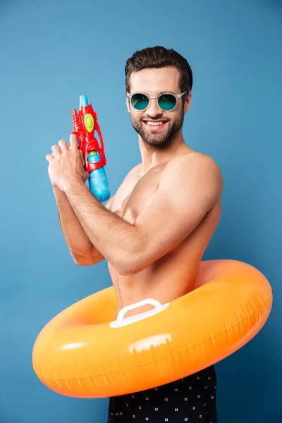 Retrato de hombre alegre mirando cámara con pistola de agua —  Fotos de Stock