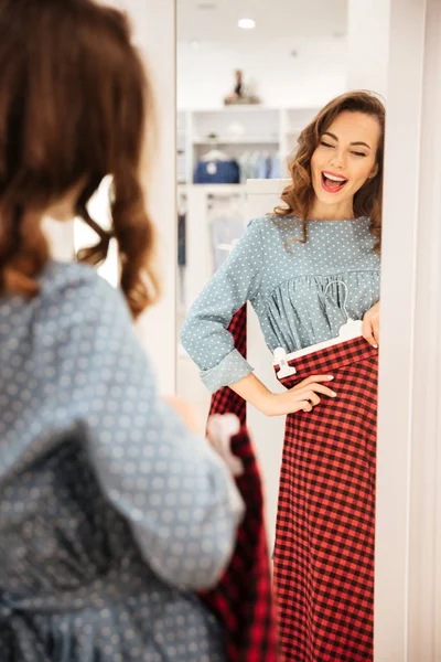 Feliz joven mujer eligiendo ropa. Mirando a un lado . — Foto de Stock