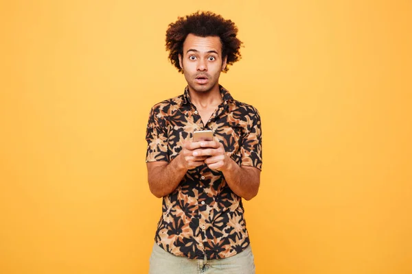 Shocked young african man chatting by phone — Stock Photo, Image