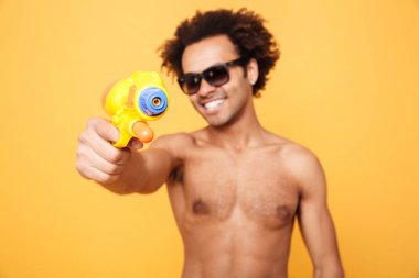 Neşeli genç Afrika adam elinde oyuncak su silah.