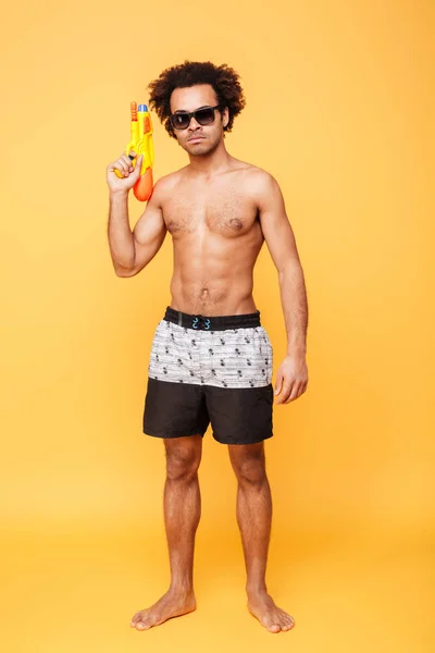 Guapo joven africano sosteniendo pistola de agua de juguete . —  Fotos de Stock