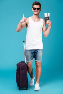 Bilet tutarak ve başparmak gösterilmesini gülümseyen adam.