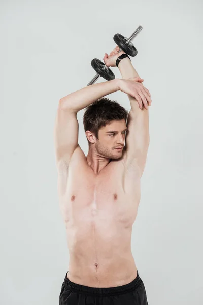 Young shirtless sportsman doing exercises with a dumbbell — Stock Photo, Image
