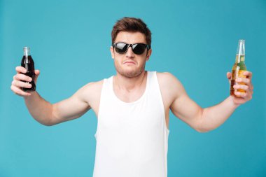 Şaşkın adam gazlı tatlı su ve bira arasında seçim yapma