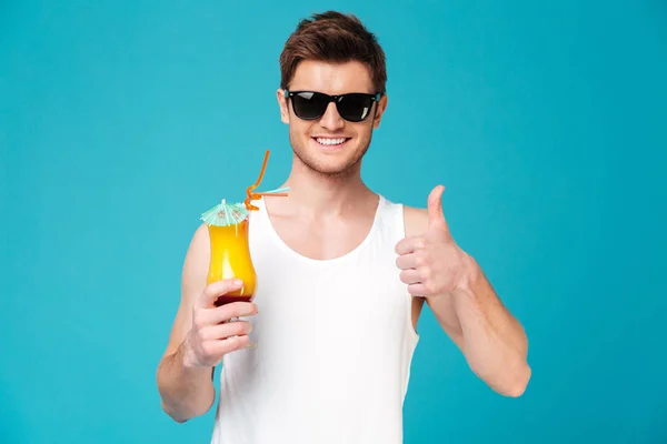 Young man in sunglasses showing cocktail and thumb up — Stock Photo, Image