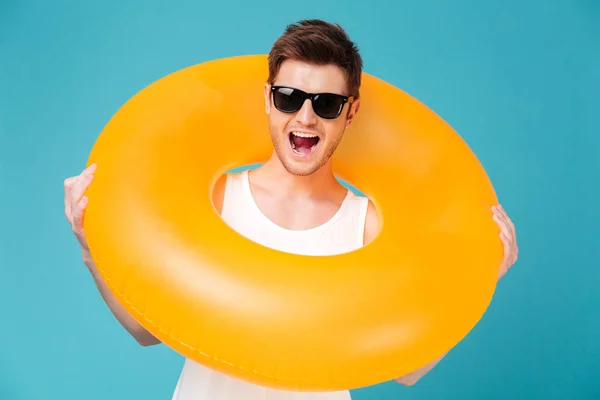 Retrato de un hombre alegre en gafas de sol sosteniendo anillo inflable — Foto de Stock